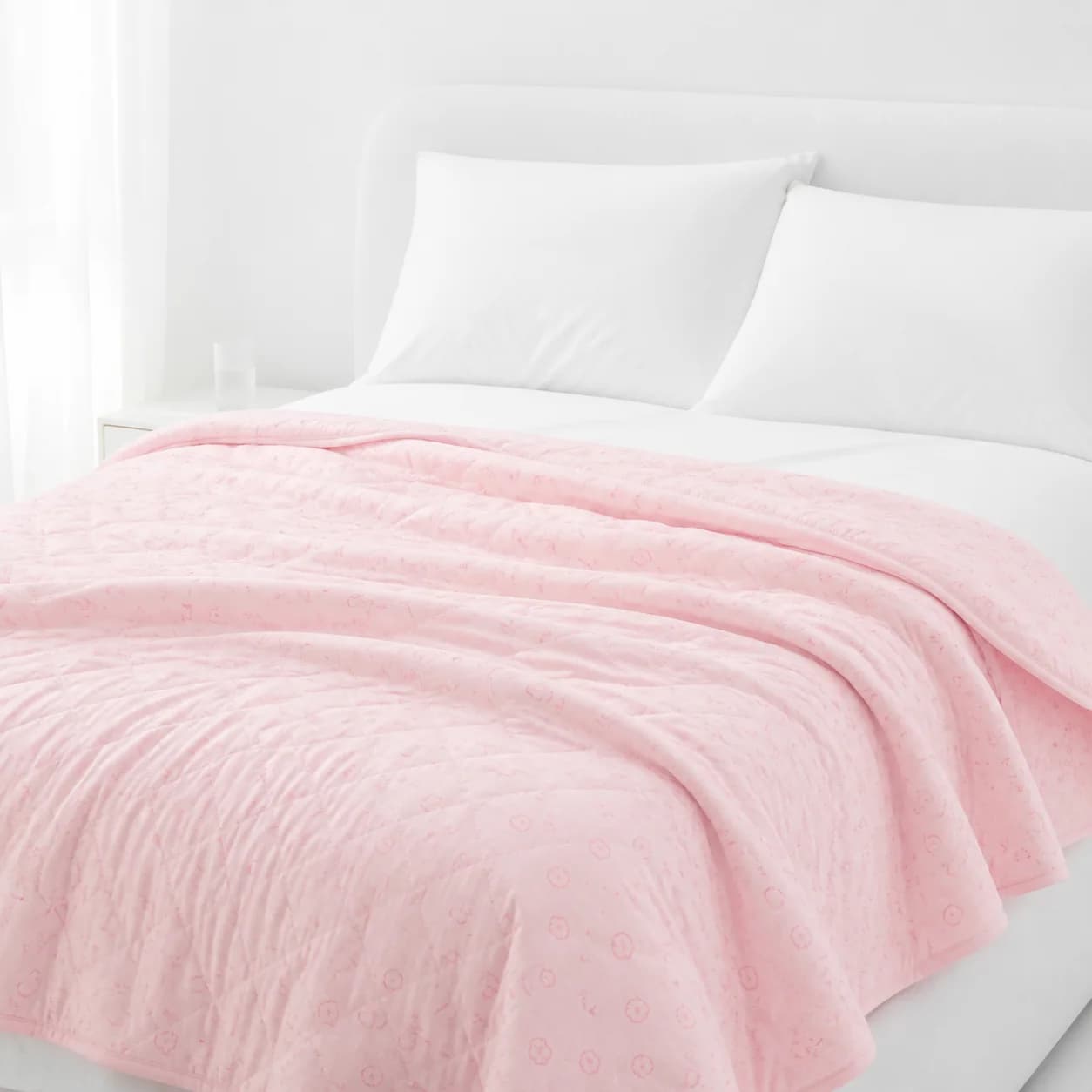 Pink flower-print cotton knit summer quilt styled on a bright white bed